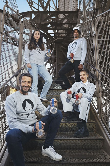 Photo de Tony Estanguet et d’athlètes posant avec des médailles olympiques dans les escaliers de la tour Eiffel